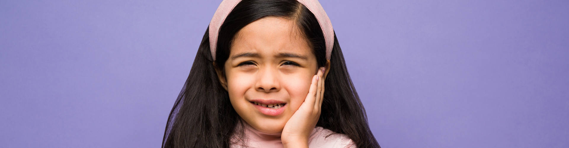 Girl holding her cheek in pain.